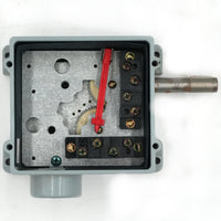 An industrial electrical junction box with a gray plastic housing, showing the internal metal terminal strip with screws, a red plastic component, and a metal shaft extending from the side.